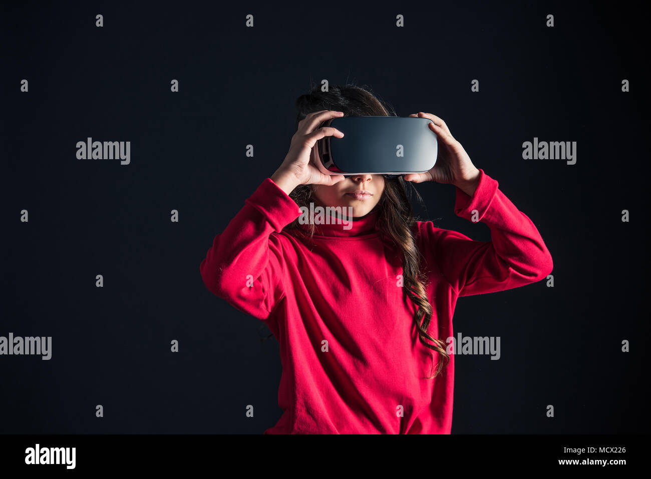 Kid mettendo su auricolare VR isolato su nero Foto Stock