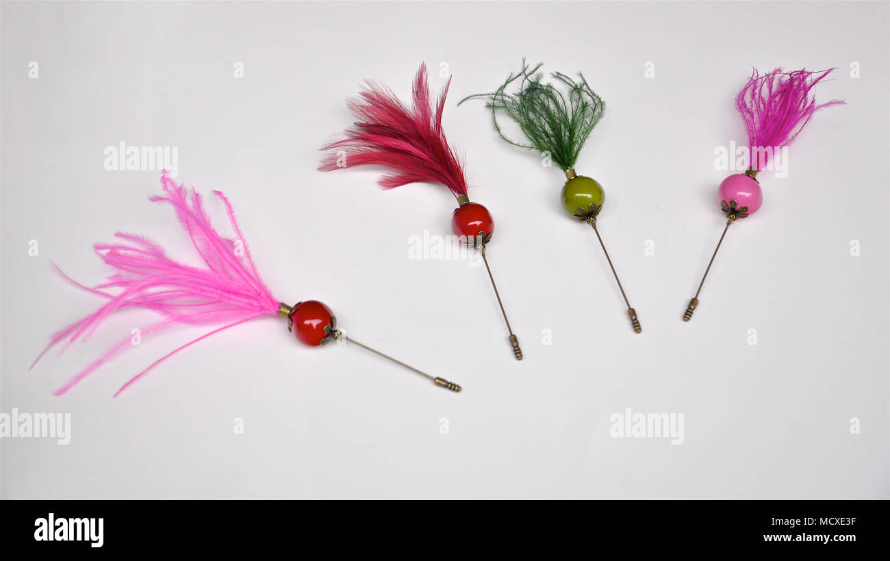 Quattro diversi colori in stile vintage abbigliamento spilla perni con pennacchi di piume su sfondo bianco. Foto Stock