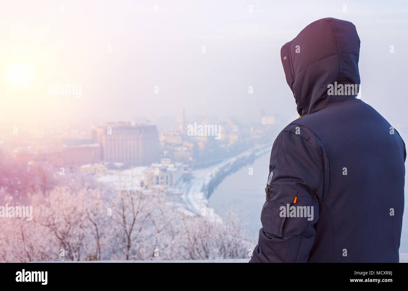 Hipster uomo viaggiatore nel cofano cercando in inverno il paesaggio della città Foto Stock