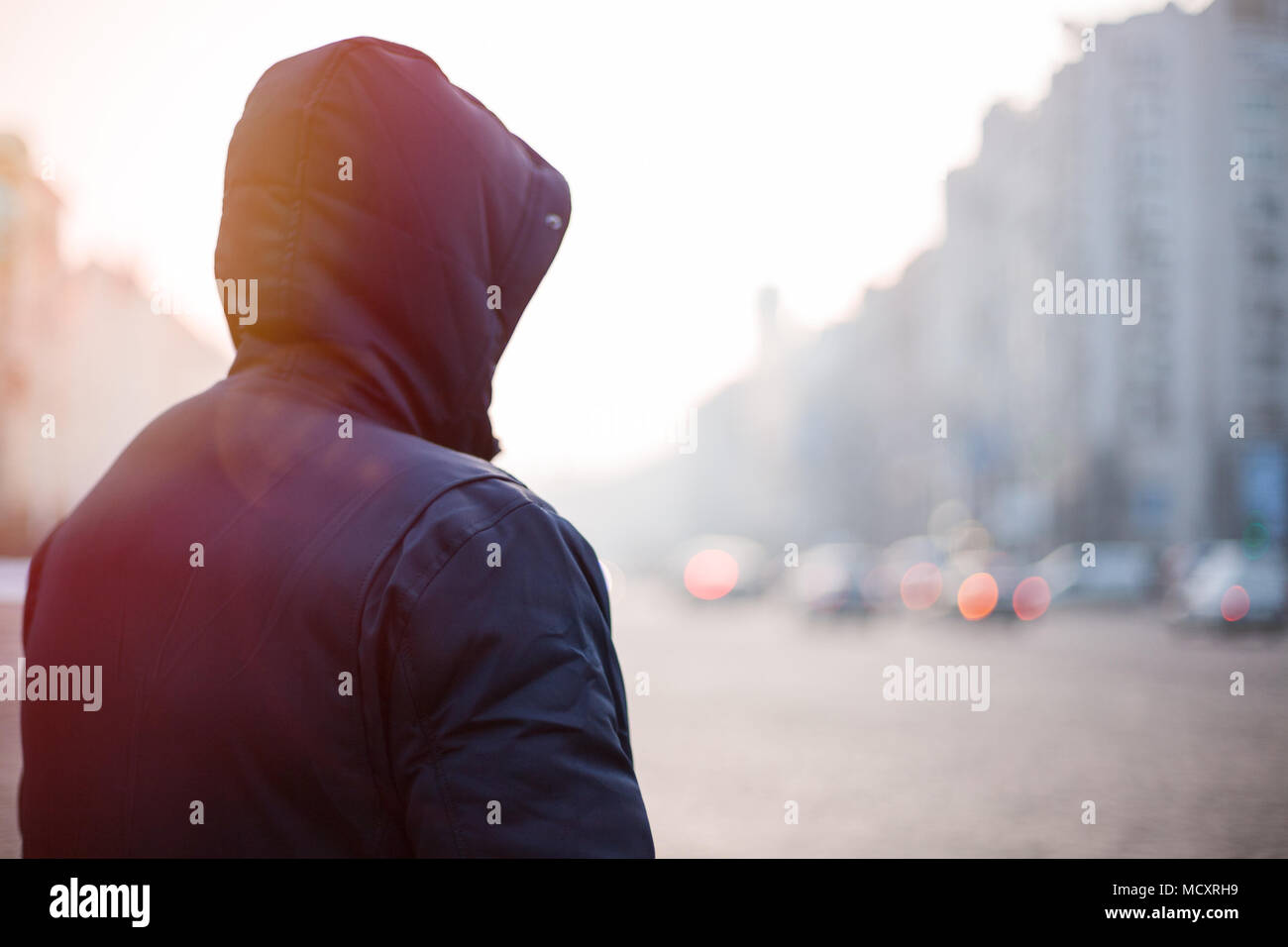 Hipster uomo nel cofano a camminare su una strada di città di sera Foto Stock