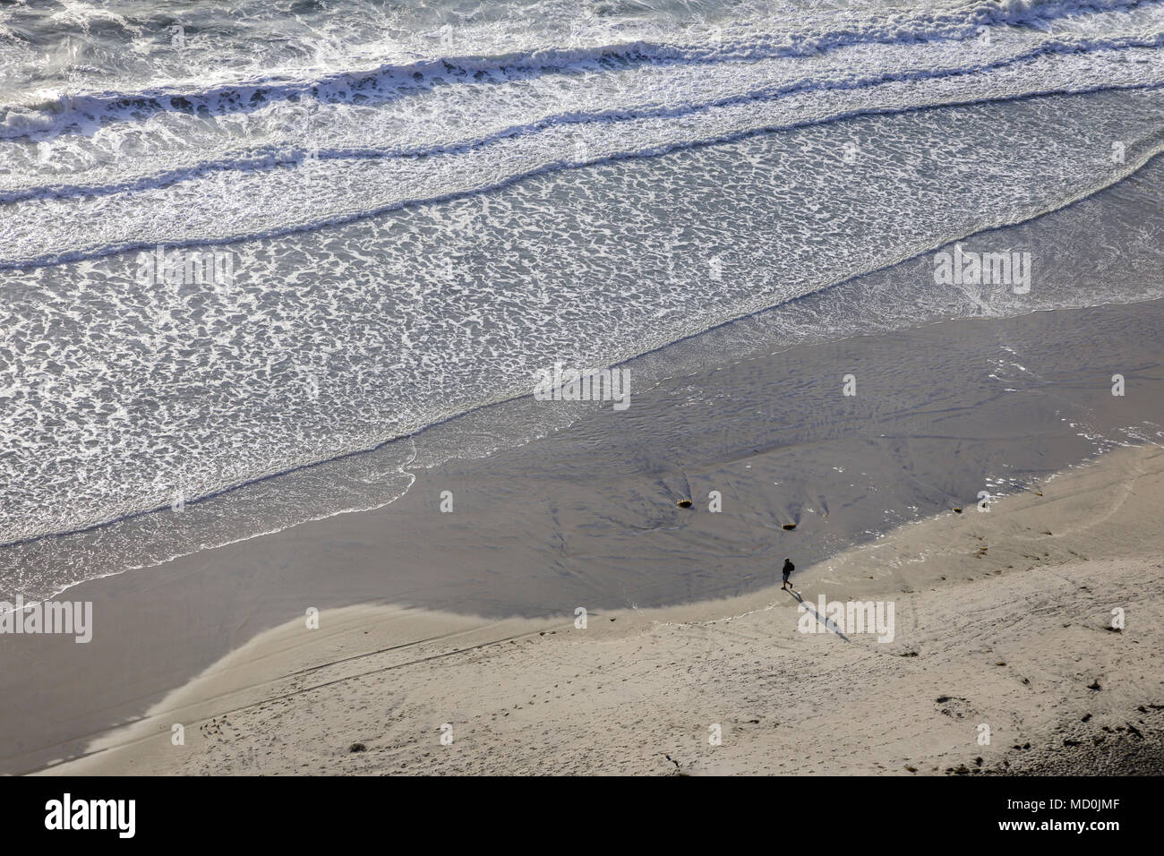 Un elevato overhead vista di una persona a piedi lungo la spiaggia con le onde in laminazione. Foto Stock