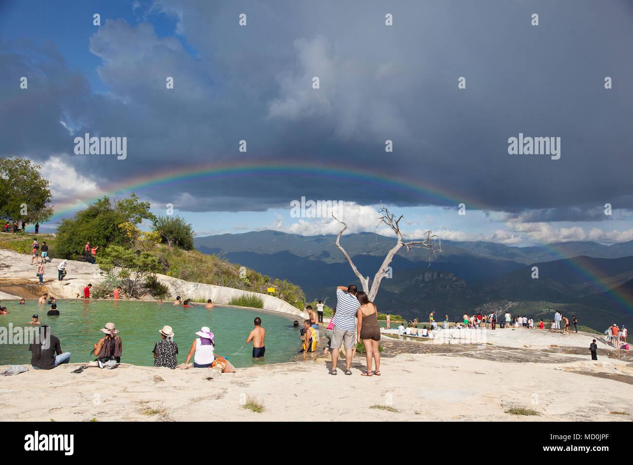 Visitatori presso le piscine di Hierve el Agua con un doppio arcobaleno in background Oaxaca, Messico Foto Stock