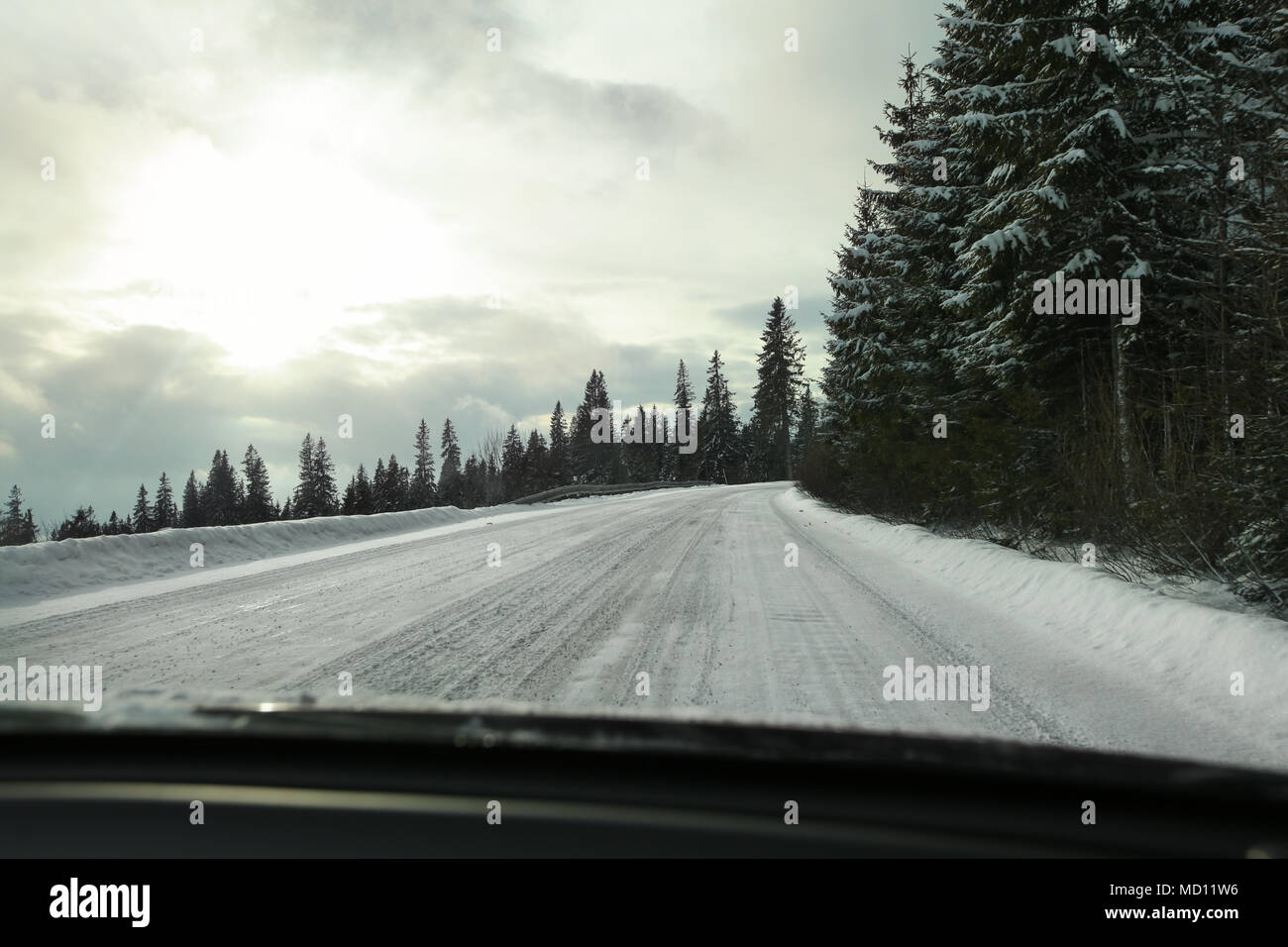 Vista dal sedile del conducente sulla strada coperta di neve forte sole accecante luce posteriore, rischioso condizioni di guida. Foto Stock