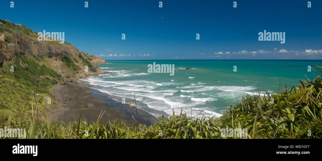 Vista remota della spiaggia con sabbia vulcanica e acqua turqoise. La posizione e' nell'area di Muriwai non lontano da Auckland, Nuova Zelanda Foto Stock