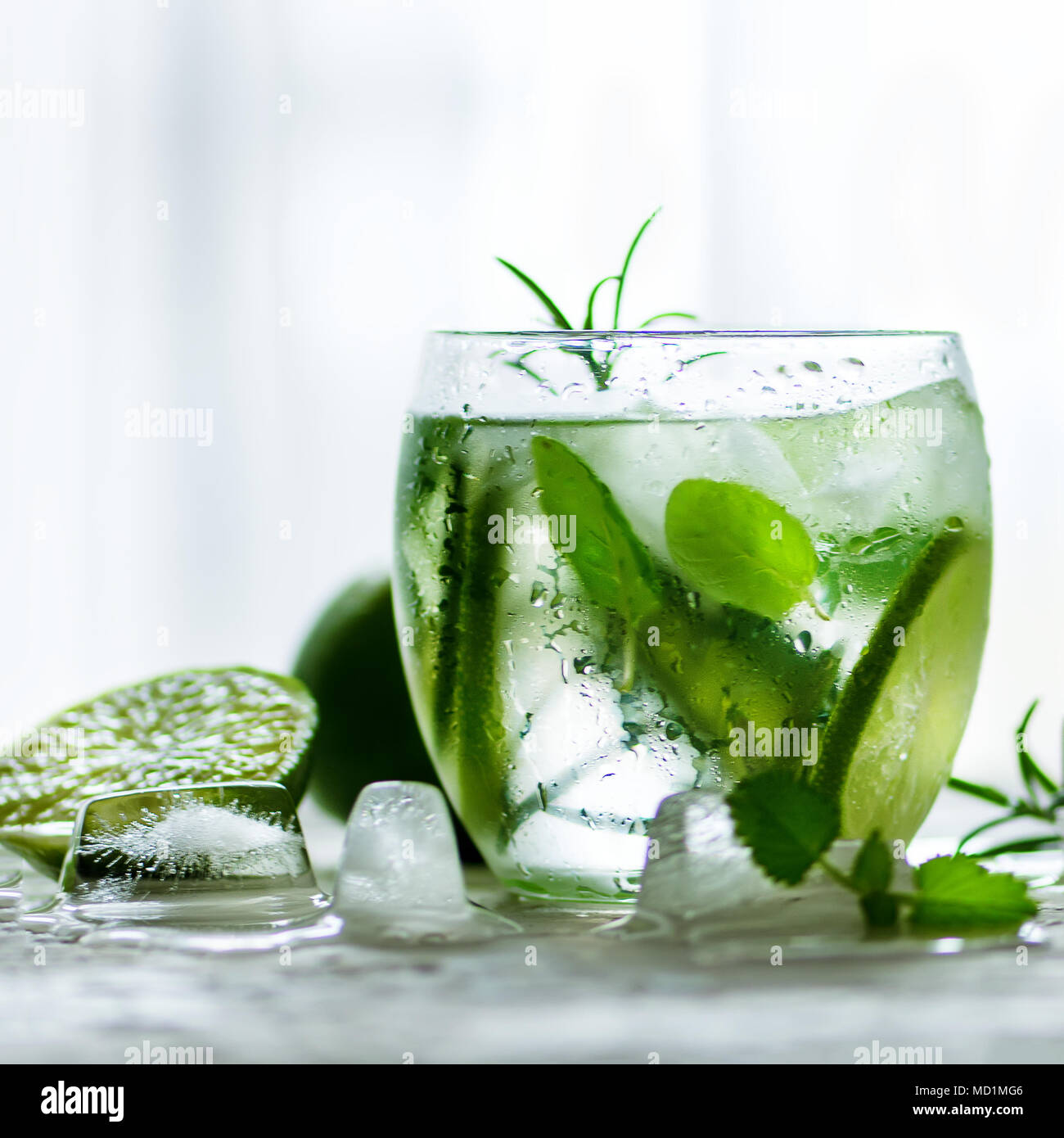 In casa di Limonata di lime con il cetriolo, il rosmarino e il ghiaccio, sfondo bianco. Bevanda fredda per le calde giornate estive. Copyspace. Foto Stock