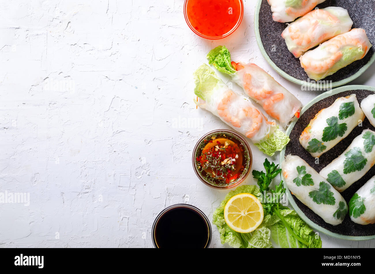 Fresh vietnamita, asiatici, cibo cinese sul telaio di cemento bianco sullo sfondo. Involtini primavera carta di riso, lattuga, insalata, vermicelli, tagliatelle, gamberi, pesce Foto Stock