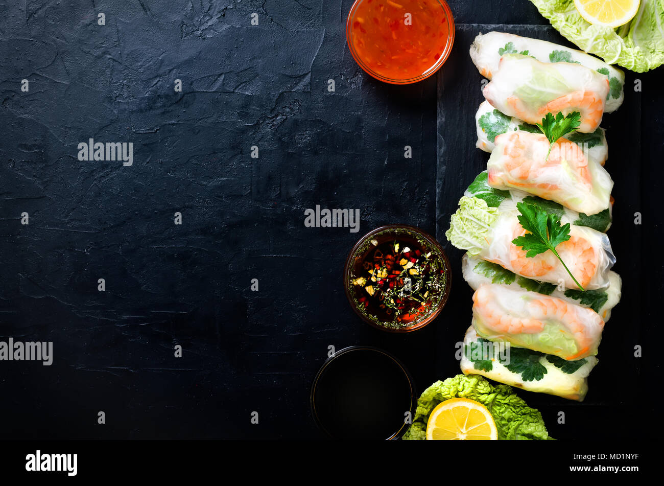 Fresh vietnamita, asiatici, cibo cinese telaio nero su sfondo di calcestruzzo. Involtini primavera carta di riso, lattuga, insalata, vermicelli, tagliatelle, gamberi, pesce Foto Stock