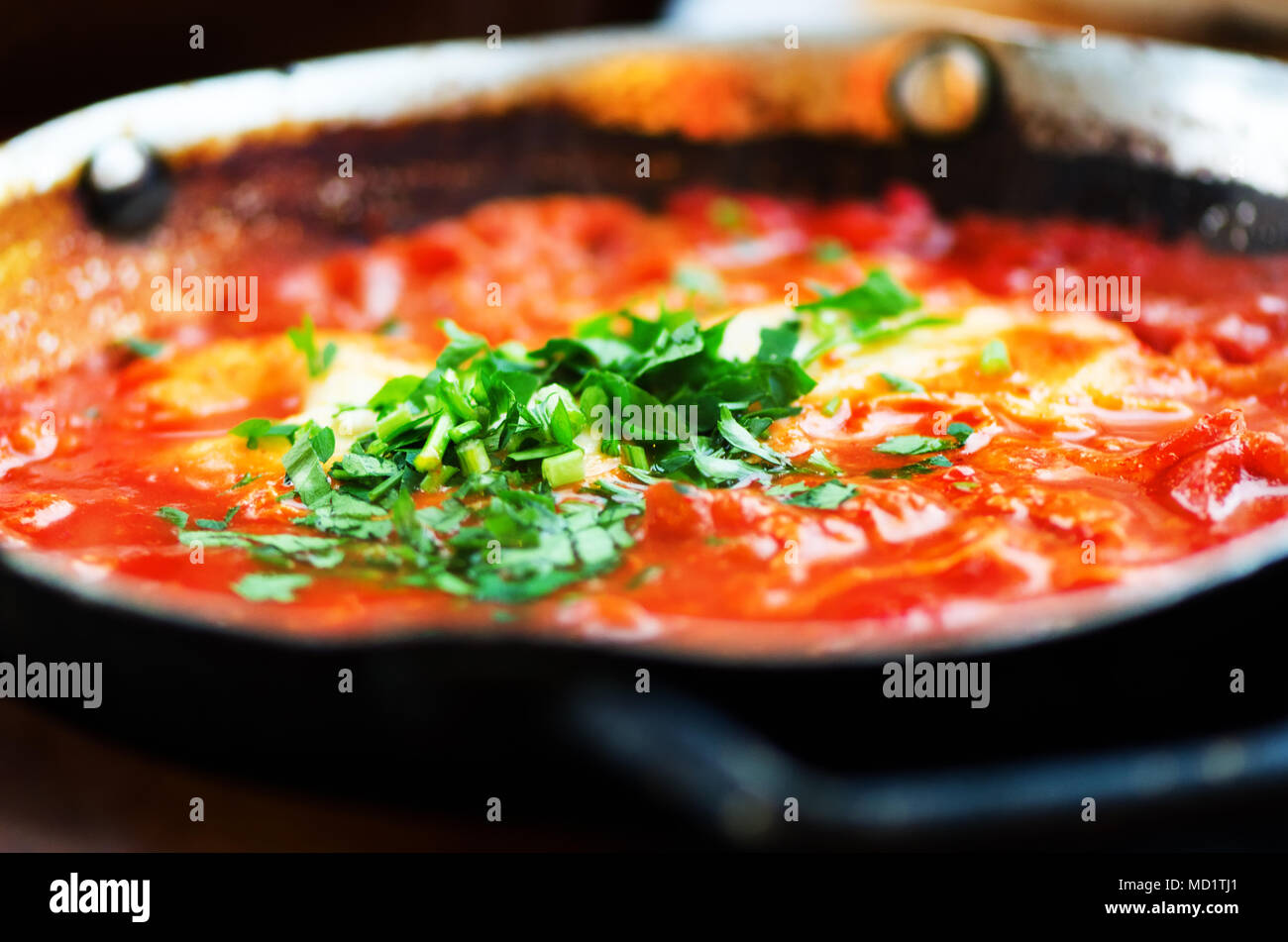 Shakshuka. Tradizionale cibo ebreo e cucina medio orientale ricetta. Uova fritte, pomodori, peperone e prezzemolo in una padella. Close up, focu selettiva Foto Stock