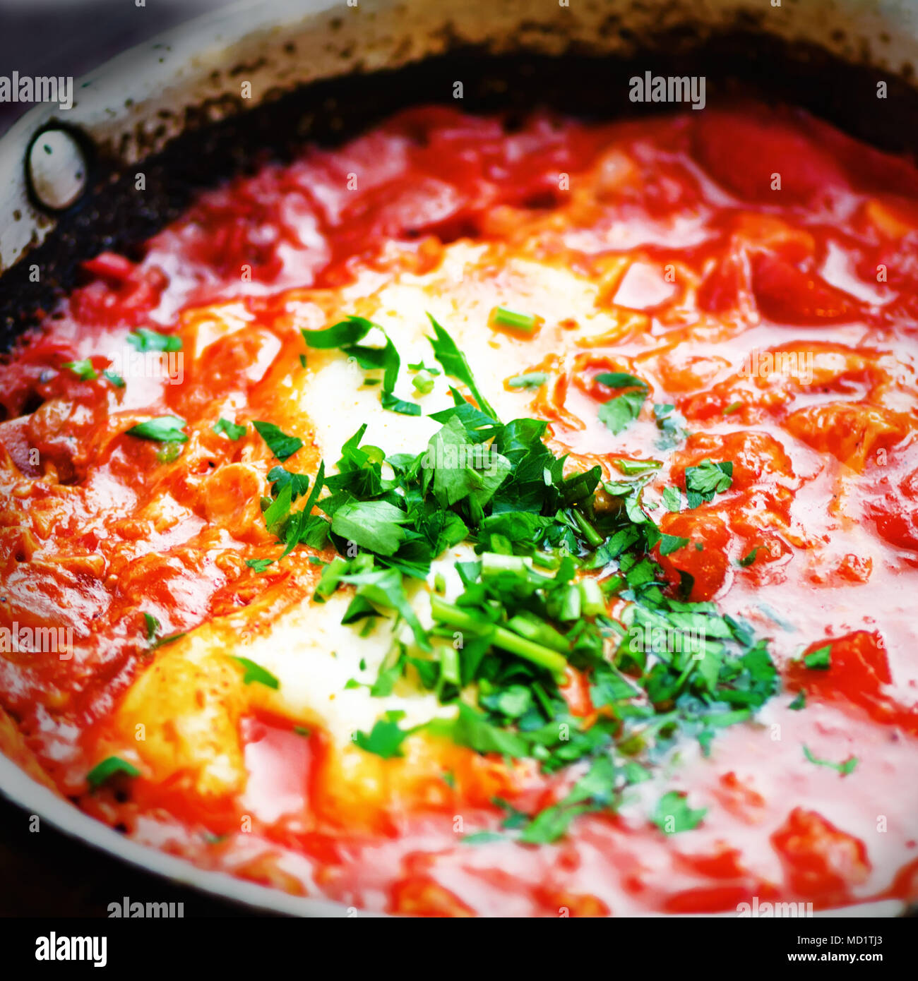 Shakshuka. Tradizionale cibo ebreo e cucina medio orientale ricetta. Uova fritte, pomodori, peperone e prezzemolo in una padella. Close up, focu selettiva Foto Stock
