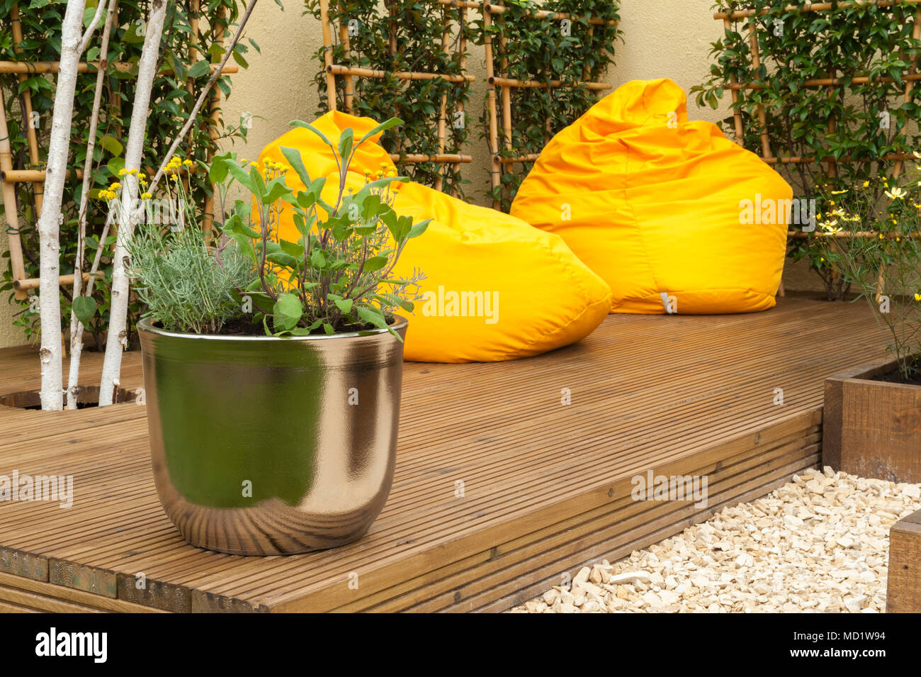 Close-up di piante in vaso e luminosi colorati, giallo sedie beanbag sul legname decking - "Il viaggio Garden' - RHS Flower Show, Tatton Park, England, Regno Unito Foto Stock