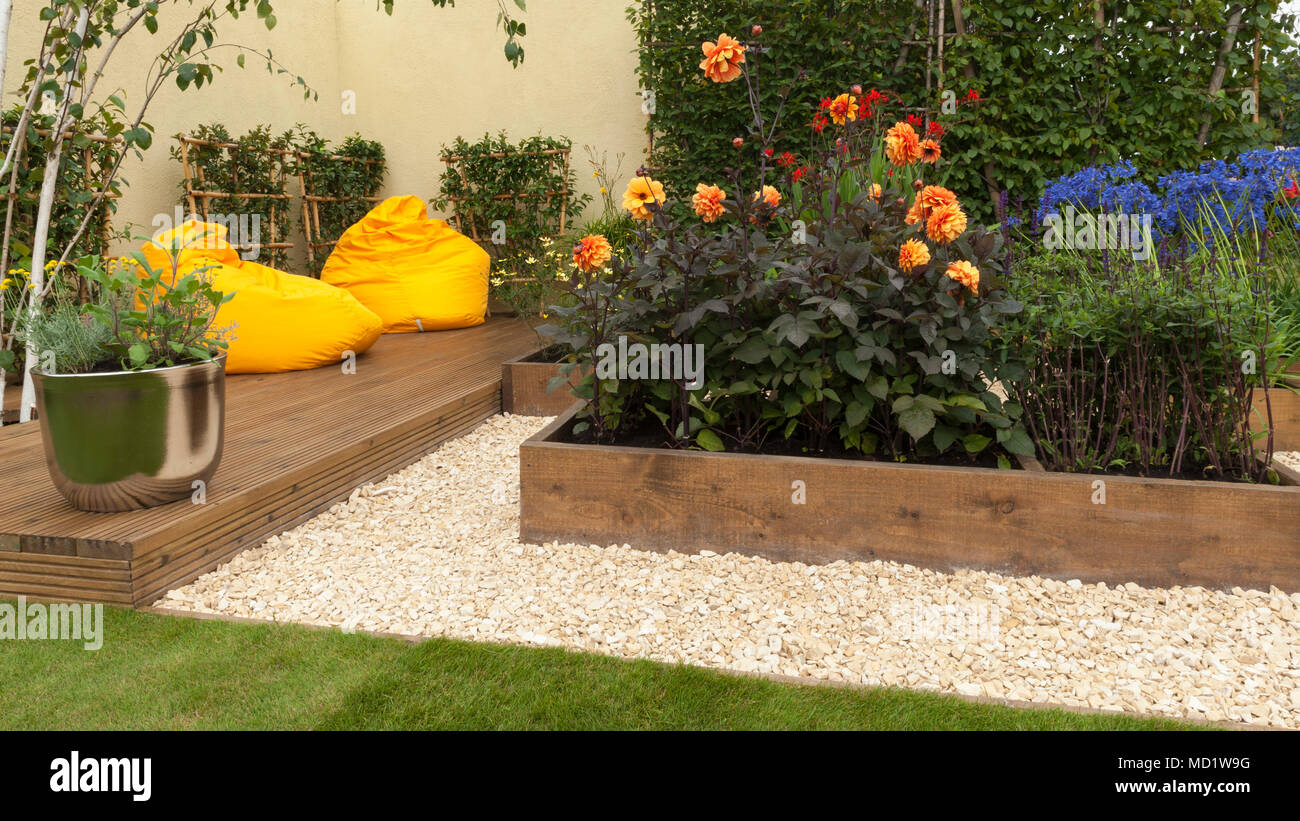 Luminose colorate di piante fiorite in letti di legno e giallo sedie beanbag su decking - "Il viaggio Garden' - RHS Flower Show, Tatton Park, England, Regno Unito Foto Stock