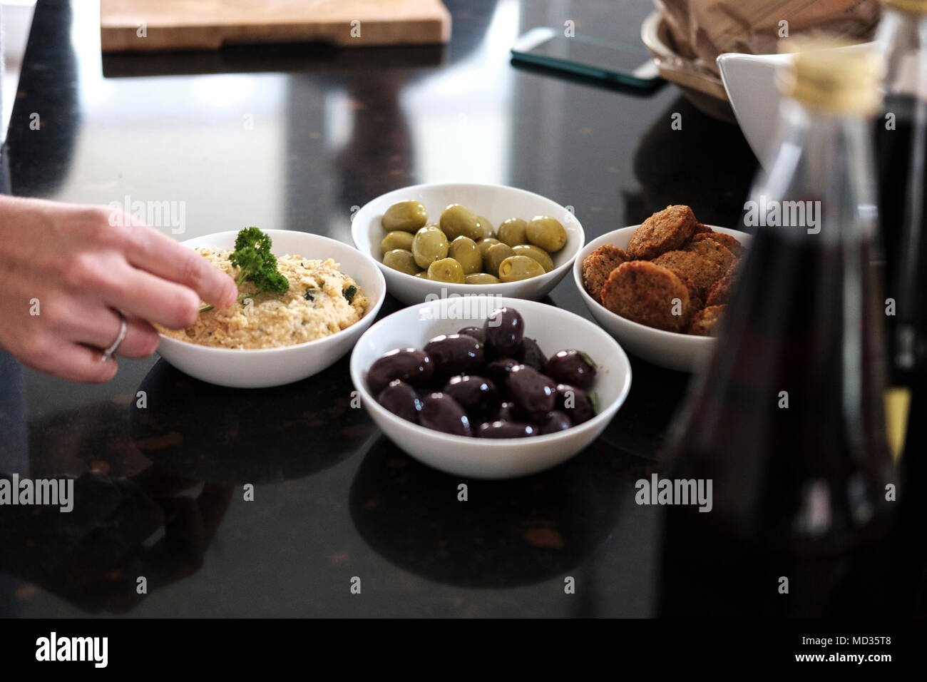 Hummus classic,olive nere e verdi e i falafel,gruppo di amici snacking casualmente su una selezione di prodotti alimentari ridendo e divertendosi. Foto Stock