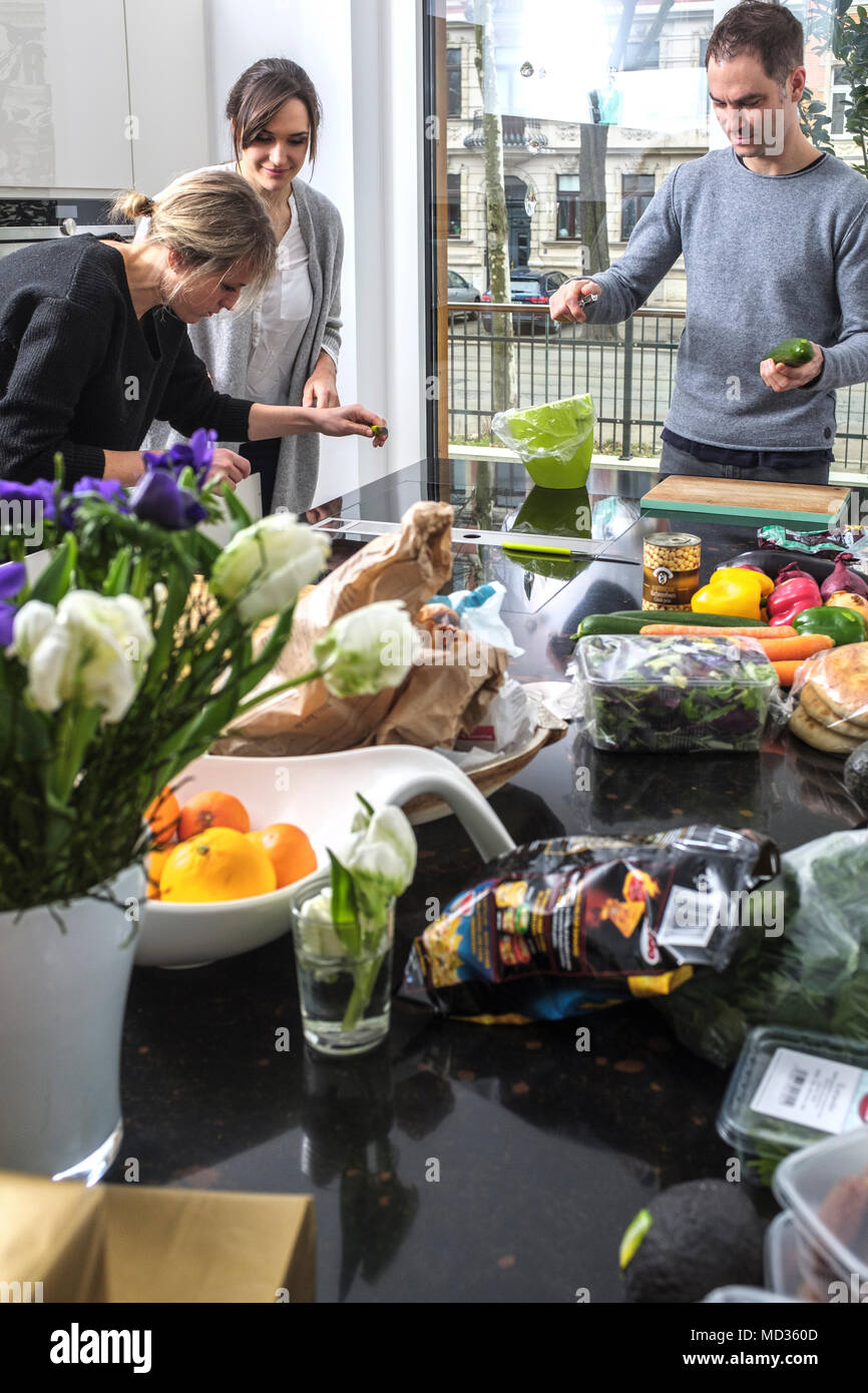 Gruppo di amici snacking casualmente su una selezione di prodotti alimentari ridendo e divertendosi. Foto Stock