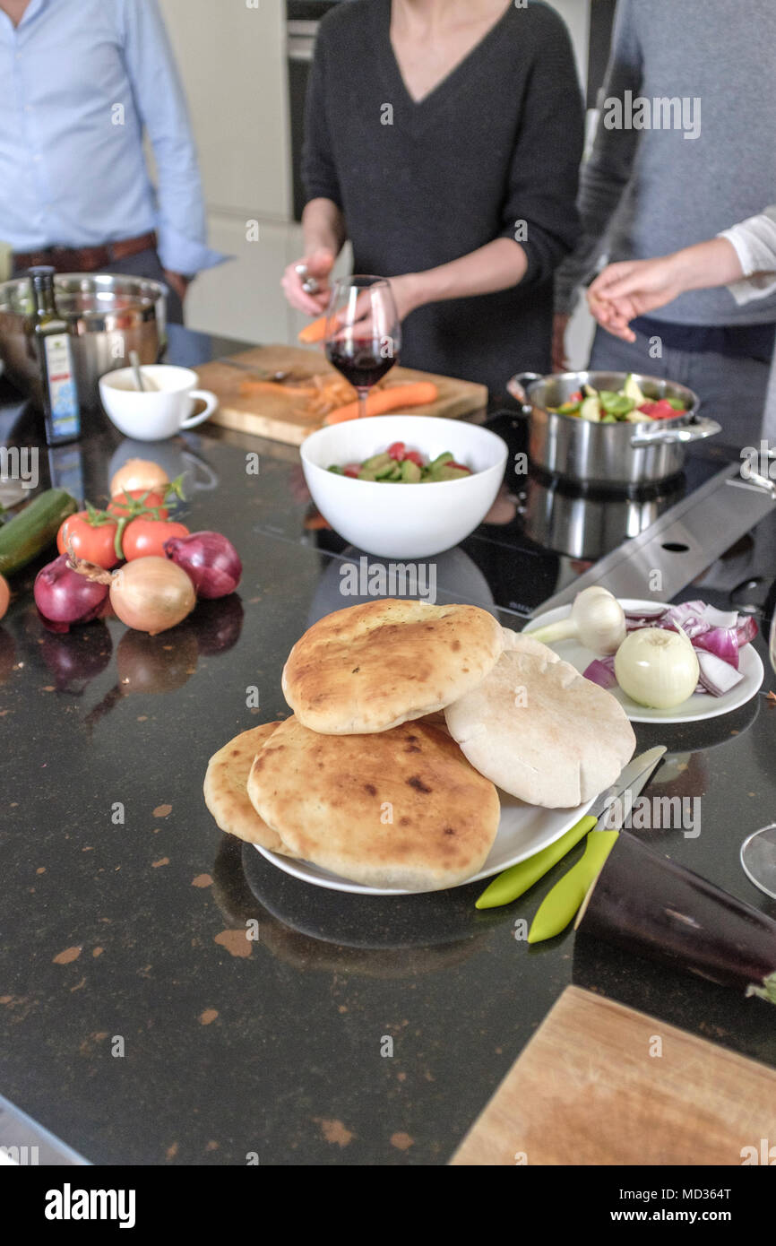 Riends cucinare insieme.Gruppo di amici snacking casualmente su una selezione di prodotti alimentari ridendo e divertendosi. Foto Stock