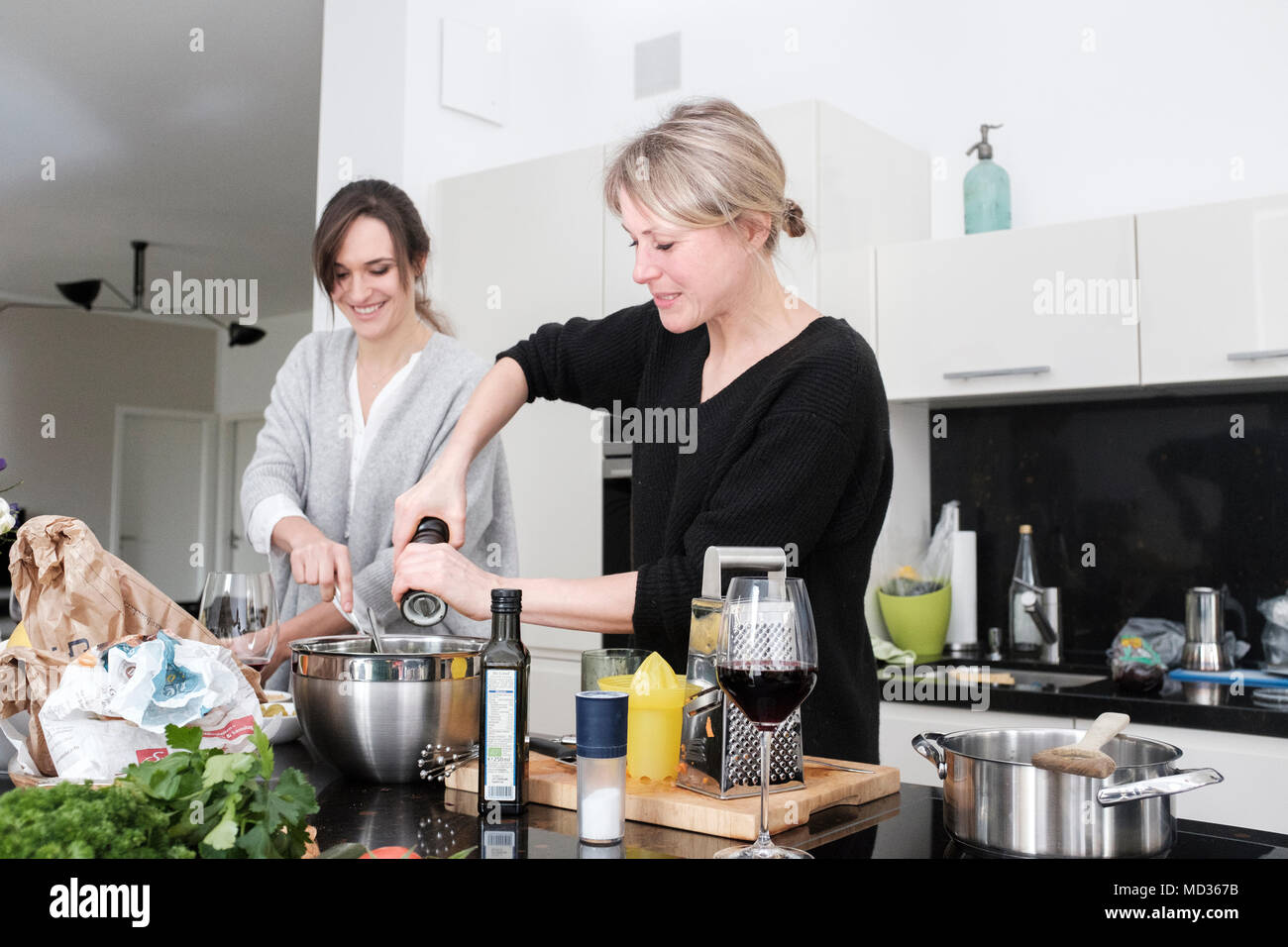 Gruppo di amici snacking casualmente su una selezione di prodotti alimentari ridendo e divertendosi. Foto Stock