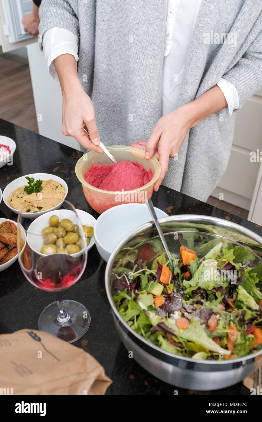La donna la preparazione di barbabietole hummus e selezione di piatti vegetariani platers-insalata mista,verde verde oliva,hummus classico. Foto Stock