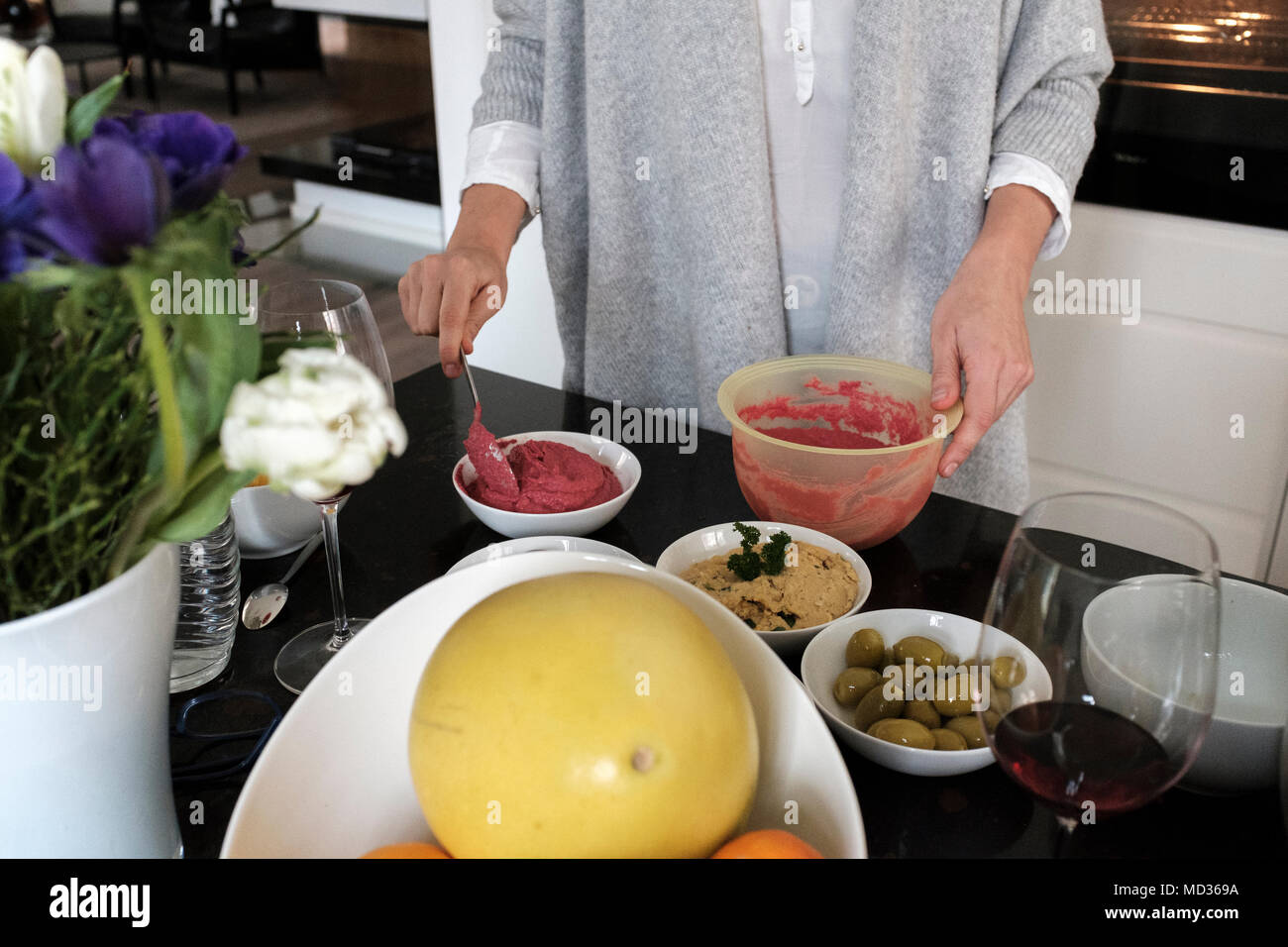 La donna la preparazione di barbabietole hummus e selezione di piatti vegetariani platers-insalata mista,verde verde oliva,hummus classico. Foto Stock