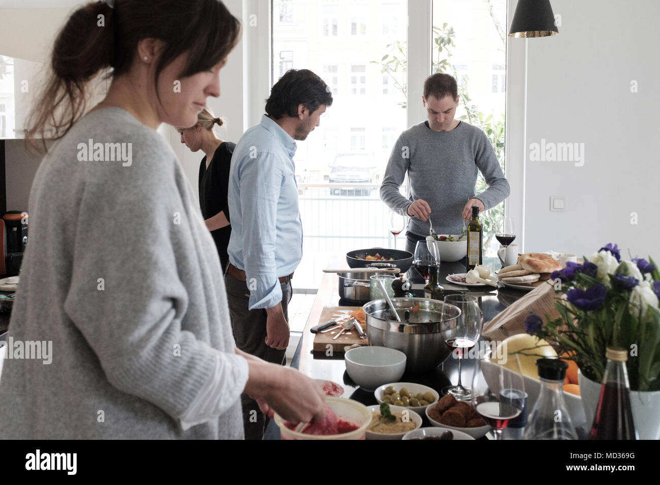 Gruppo di amici snacking casualmente su una selezione di prodotti alimentari ridendo e divertendosi. Foto Stock