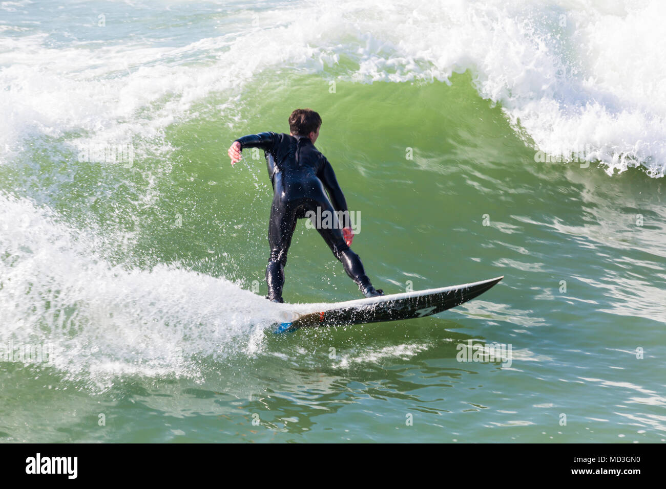 Bournemouth Dorset, Regno Unito. Il 18 aprile 2018. Regno Unito meteo: grandi onde fornire ideali condizioni di surf a Bournemouth Beach il giorno più caldo dell'anno finora. Surfer in azione sulla tavola da surf a cavallo di un onda. Foto Stock