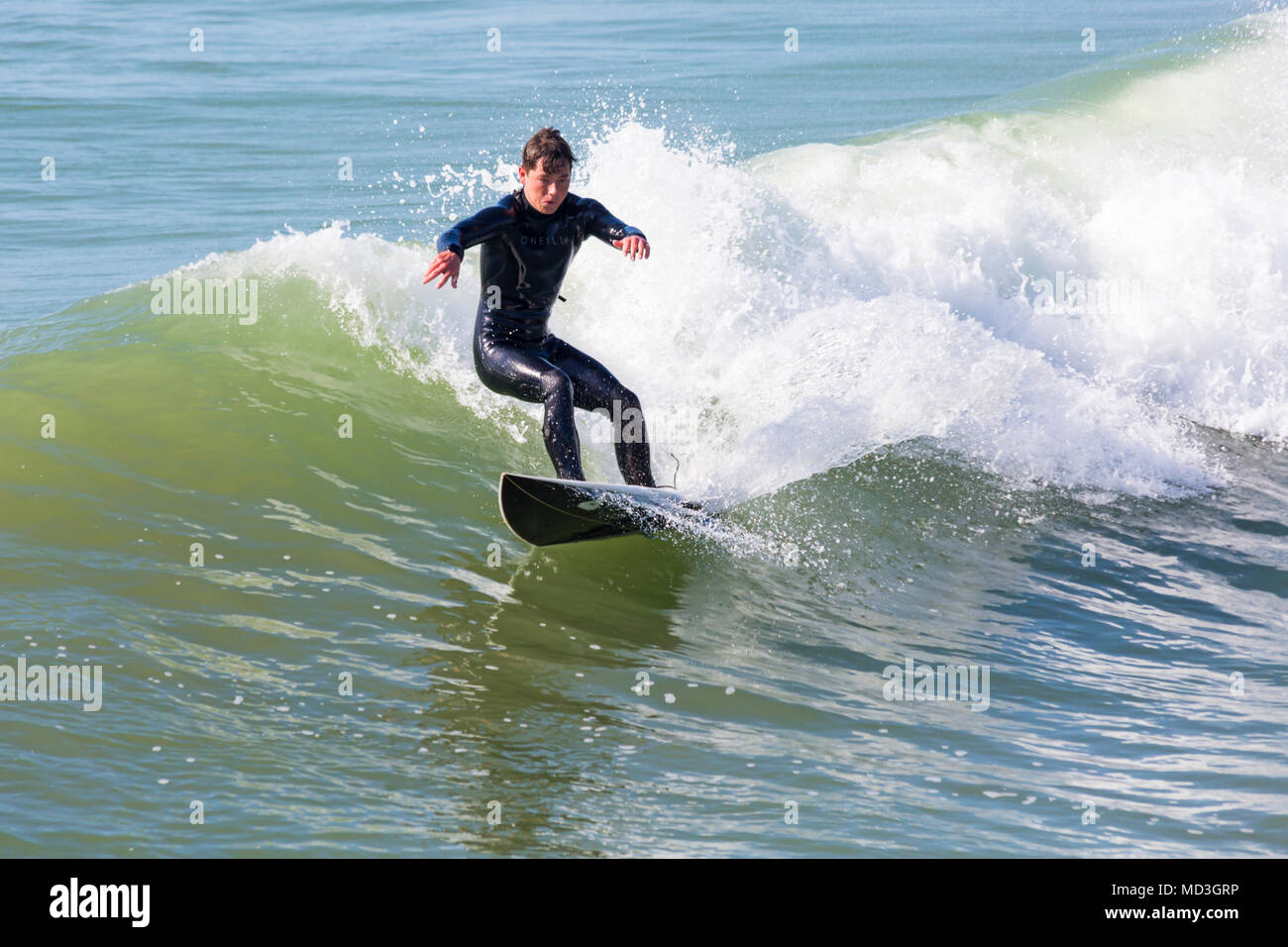 Bournemouth Dorset, Regno Unito. Il 18 aprile 2018. Regno Unito meteo: grandi onde fornire ideali condizioni di surf a Bournemouth Beach il giorno più caldo dell'anno finora. Surfer in azione sulla tavola da surf a cavallo di un onda. Foto Stock
