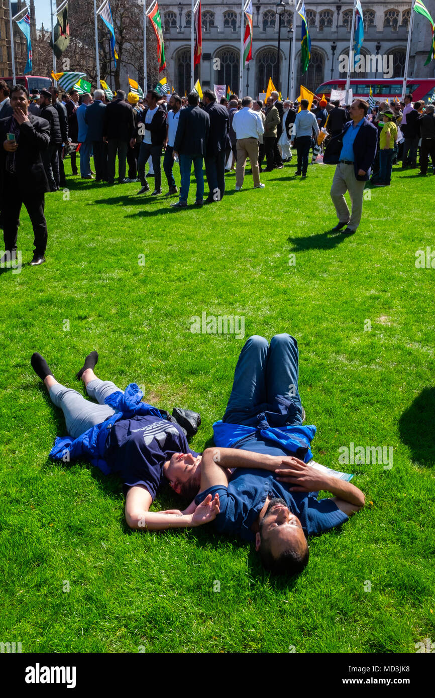 Regno Unito meteo: coppia giovane addormentarsi sotto il caldo sole in Piazza del Parlamento a Londra, completamente ignaro delle enormi e molto forte anti-Modi protesta intorno a loro il giorno più caldo dell'anno finora, mercoledì 18 aprile 2018 Foto Stock