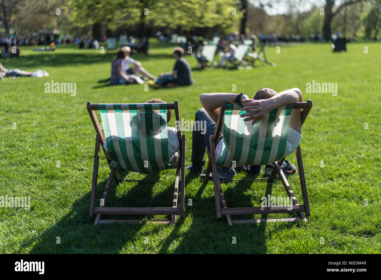 Londra, Regno Unito. Il 18 aprile 2018. Le persone che si godono la calda primavera meteo su sedie a sdraio in St James Park su un giorno quando la temperatura ha raggiunto 25 gradi a Londra. Foto data: mercoledì 18 aprile, 2018. Foto: Roger Garfield/Alamy Live News Foto Stock