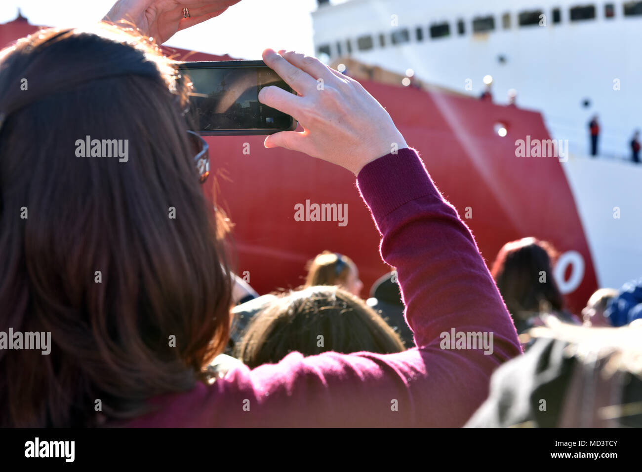 Un membro della famiglia prende una fotografia di un membro dell'equipaggio a bordo del guardacoste stella polare come l'equipaggio attracca al molo di base a Seattle, 16 marzo 2018. La Seattle-basato Stella Polare porta sinistra nel mese di dicembre per l'Antartide per supportare il funzionamento Deep Freeze 2018, il militare degli Stati Uniti a dare il suo contributo di US Programma antartico, che è gestito dalla Fondazione di Scienza Nazionale. Stati Uniti Coast Guard foto di Sottufficiali di seconda classe Flockerzi Ali. Foto Stock