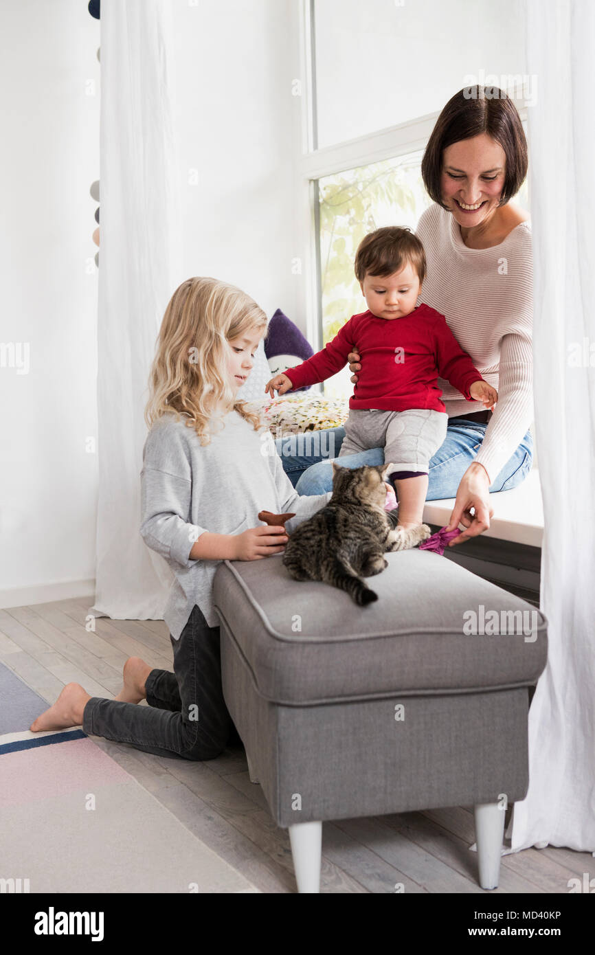 La madre e le sue due figlie giocare con Pet cat Foto Stock