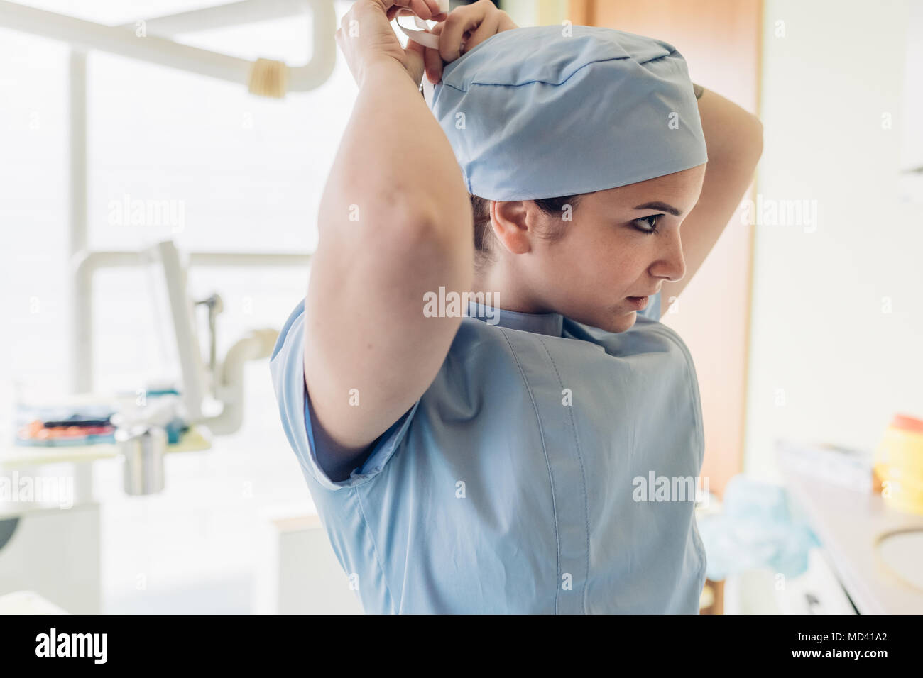 Femmina di dentista in studio dentistico, mettendo sul cappuccio chirurgico Foto Stock