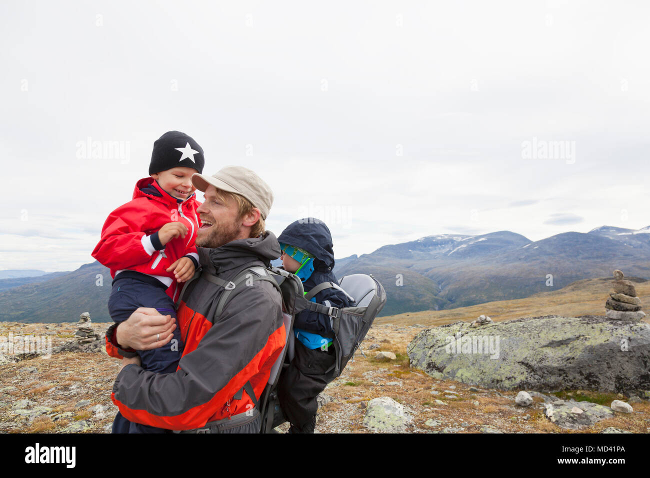 Escursionista maschio con figli nel paesaggio di montagna, parco nazionale di Jotunheimen, Lom, Oppland, Norvegia Foto Stock