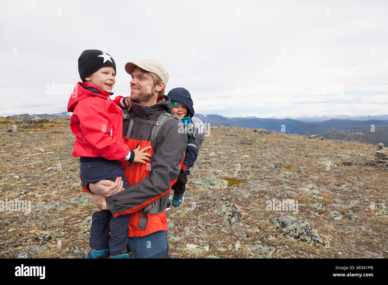 Escursionista maschio con figli nel paesaggio di montagna, parco nazionale di Jotunheimen, Lom, Oppland, Norvegia Foto Stock