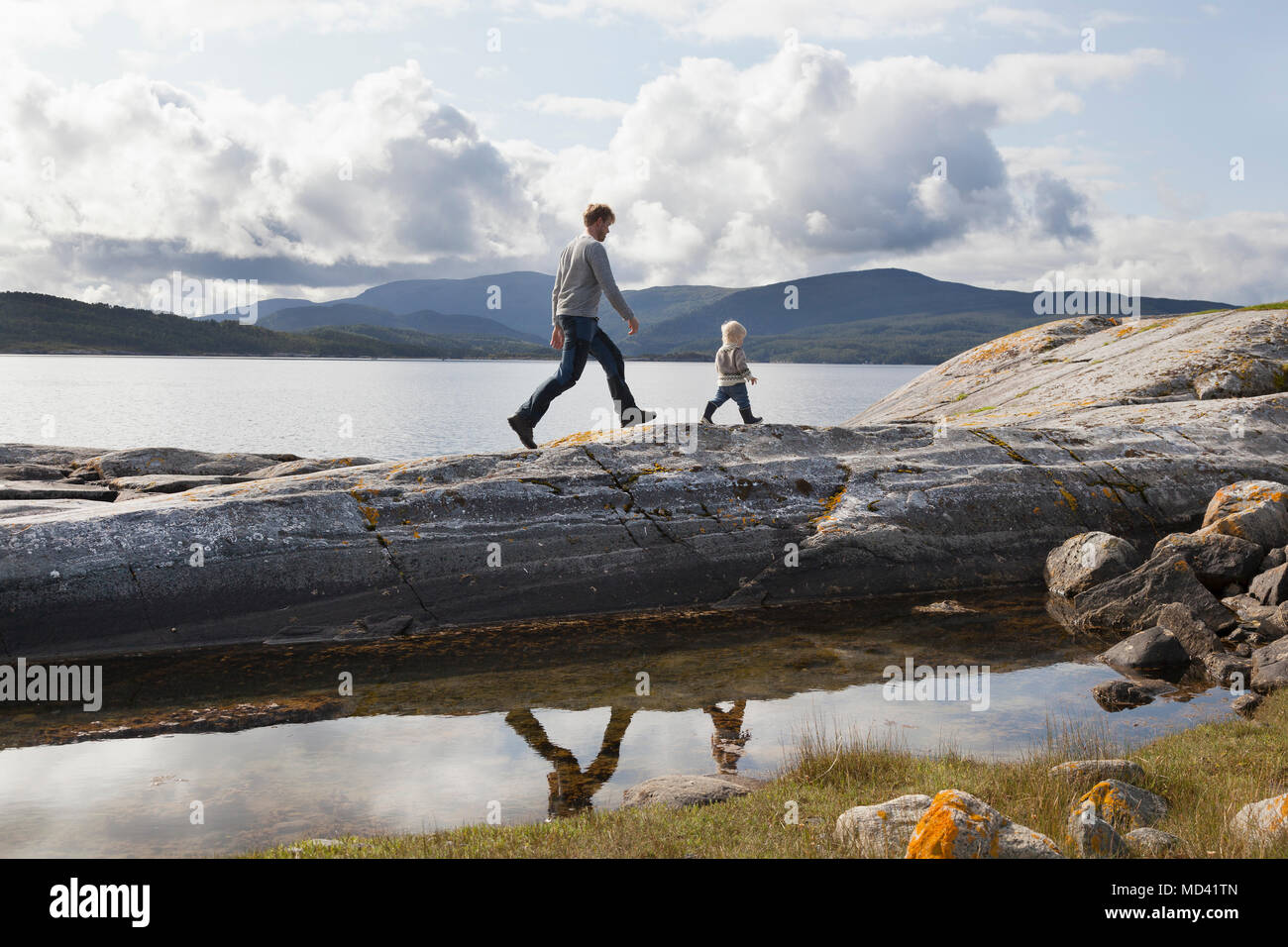 Uomo e figlio camminando sul fiordo formazione di roccia, Aure, More og Romsdal, Norvegia Foto Stock
