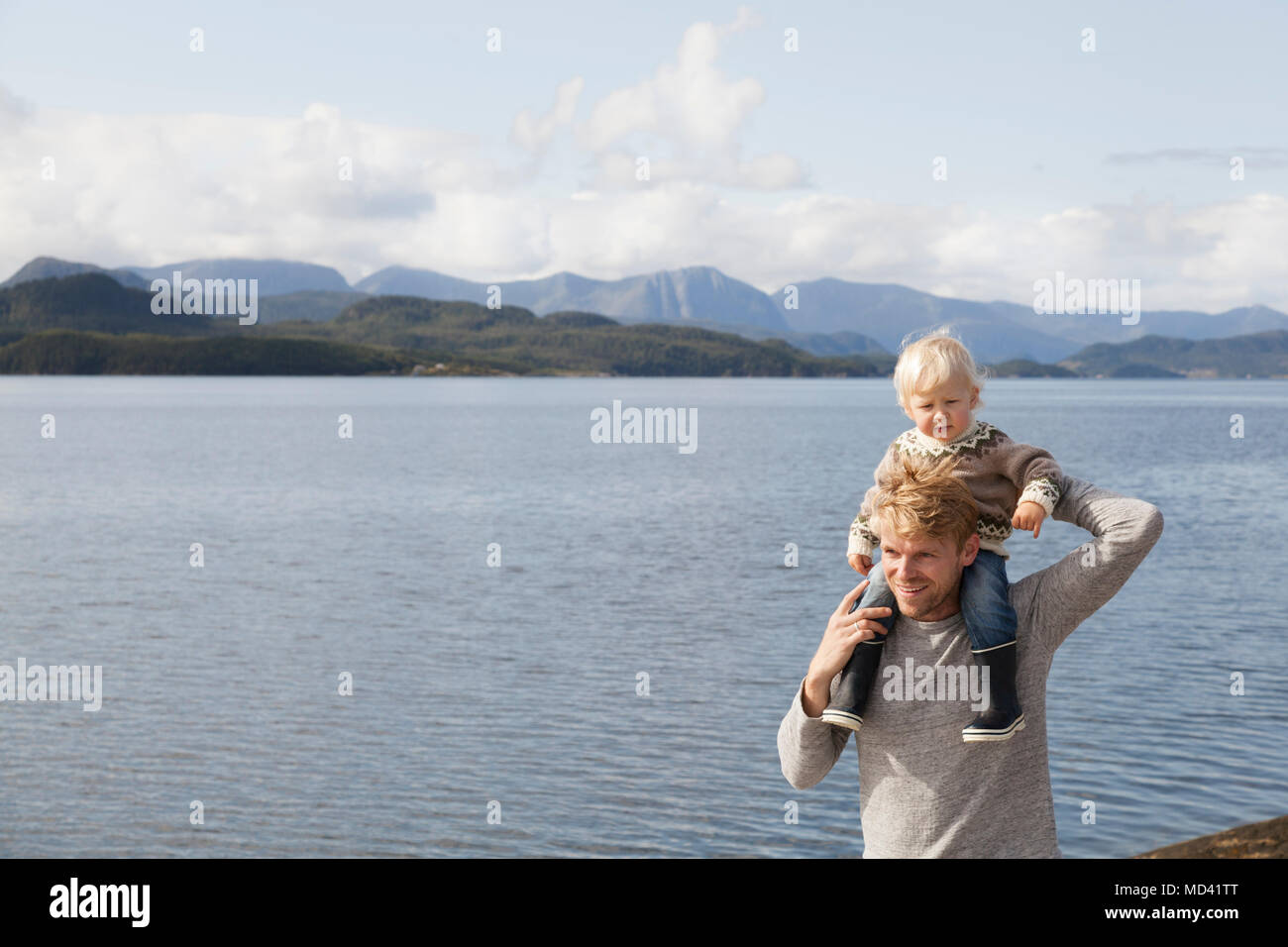 L uomo dando figlio giro spalla dal fiordo, Aure, More og Romsdal, Norvegia Foto Stock