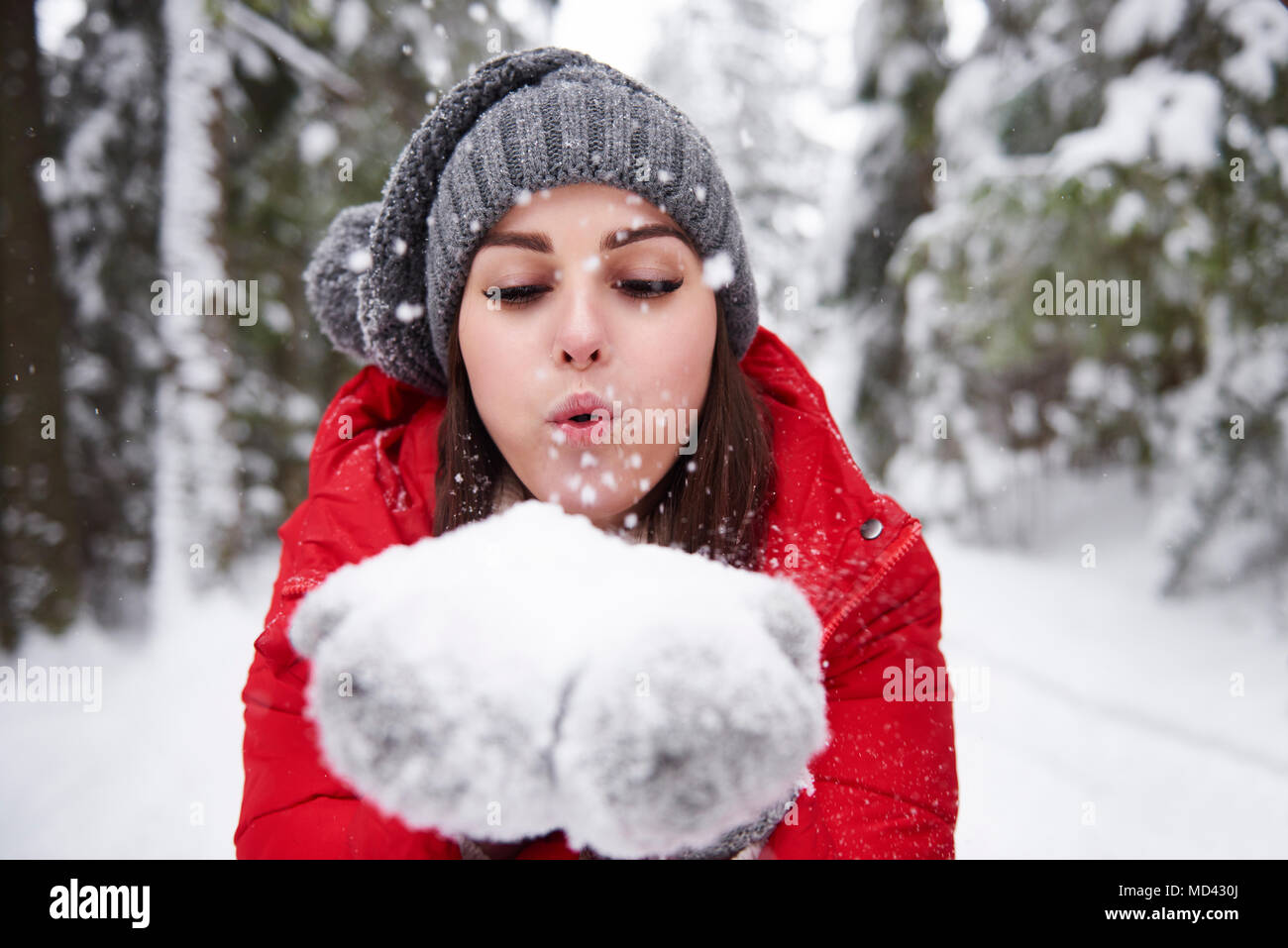 Giovane donna fiocchi di neve di soffiatura off mani Foto Stock