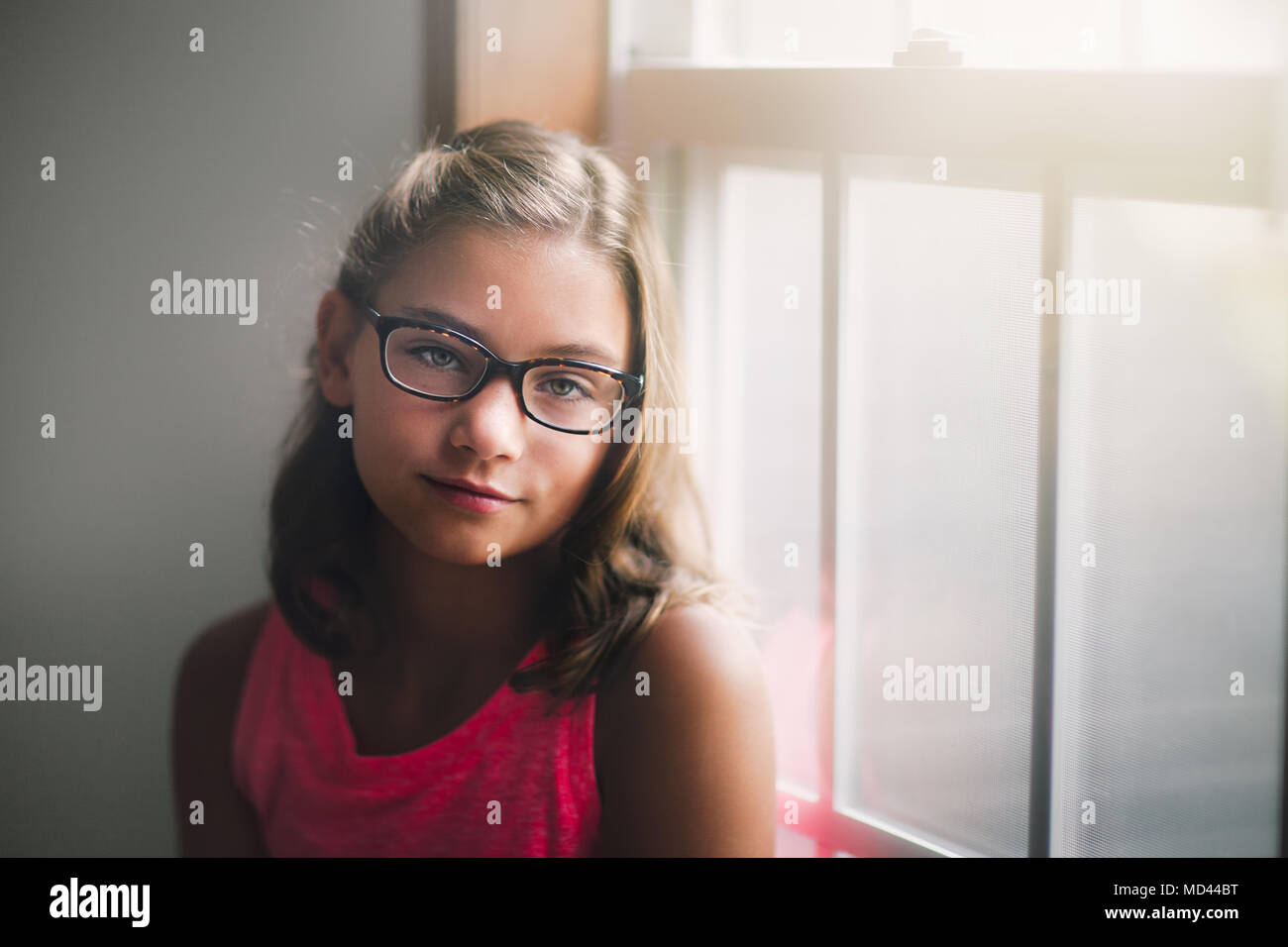 Ritratto di giovane ragazza con gli occhiali, in piedi accanto alla finestra, pensieroso expression Foto Stock