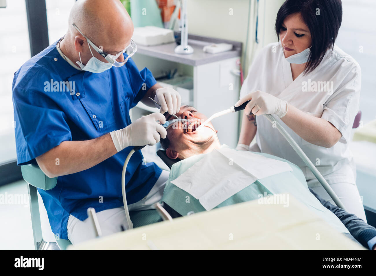 Dentista e infermiere di eseguire la procedura sul paziente di sesso maschile Foto Stock