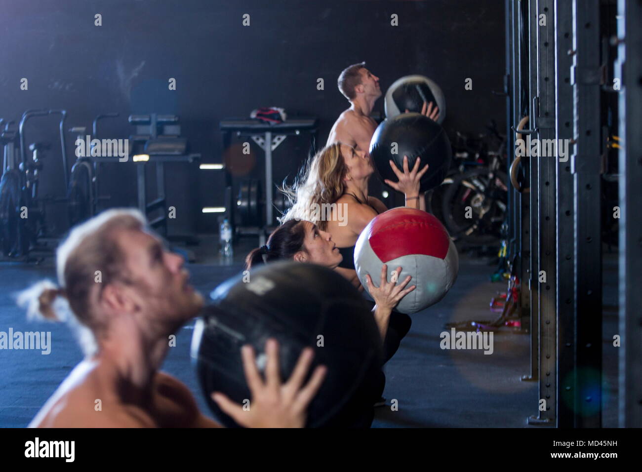 Gruppo di persone che esercitano in palestra, utilizzando sfere di medicina Foto Stock