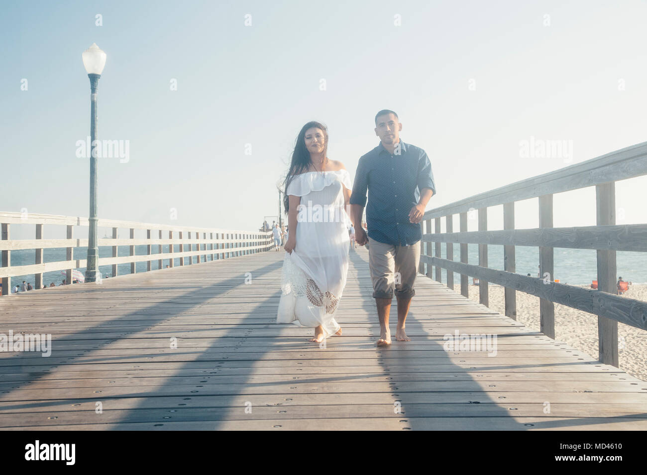 Giovane camminando lungo il molo, tenendo le mani, Seal Beach, California, Stati Uniti d'America Foto Stock