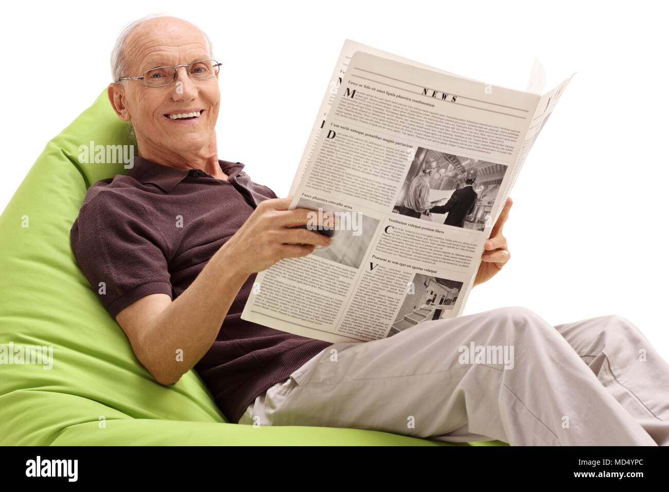 Uomo anziano con un giornale seduto su una beanbag e sorridente isolati su sfondo bianco Foto Stock