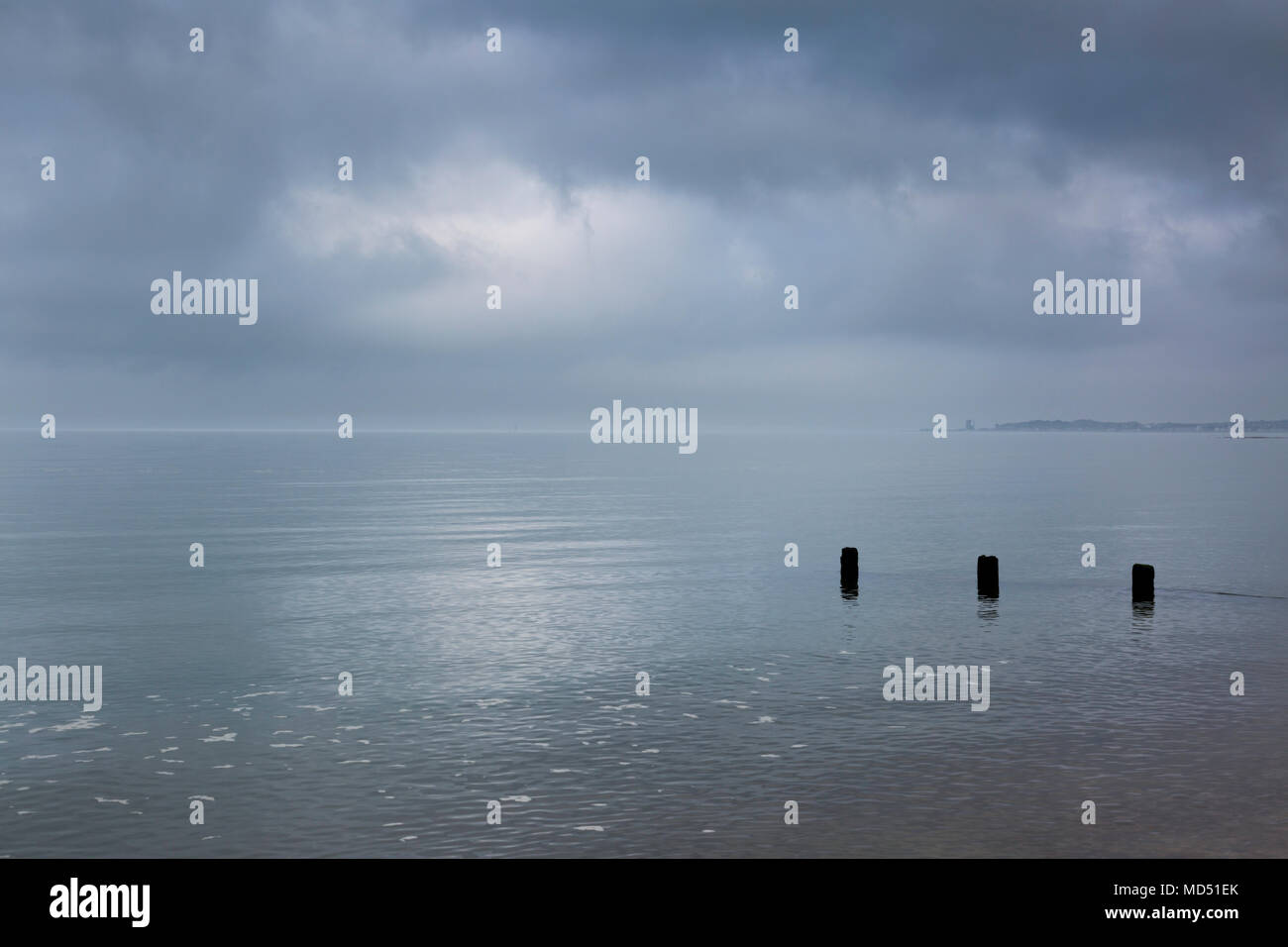 Morbida luce mistica e basse nubi si riflette sul mare tranquillo che sembra vetro a Seasalter vicino a Whitstable sulla costa della contea del Kent settentrionale, UK. Foto Stock