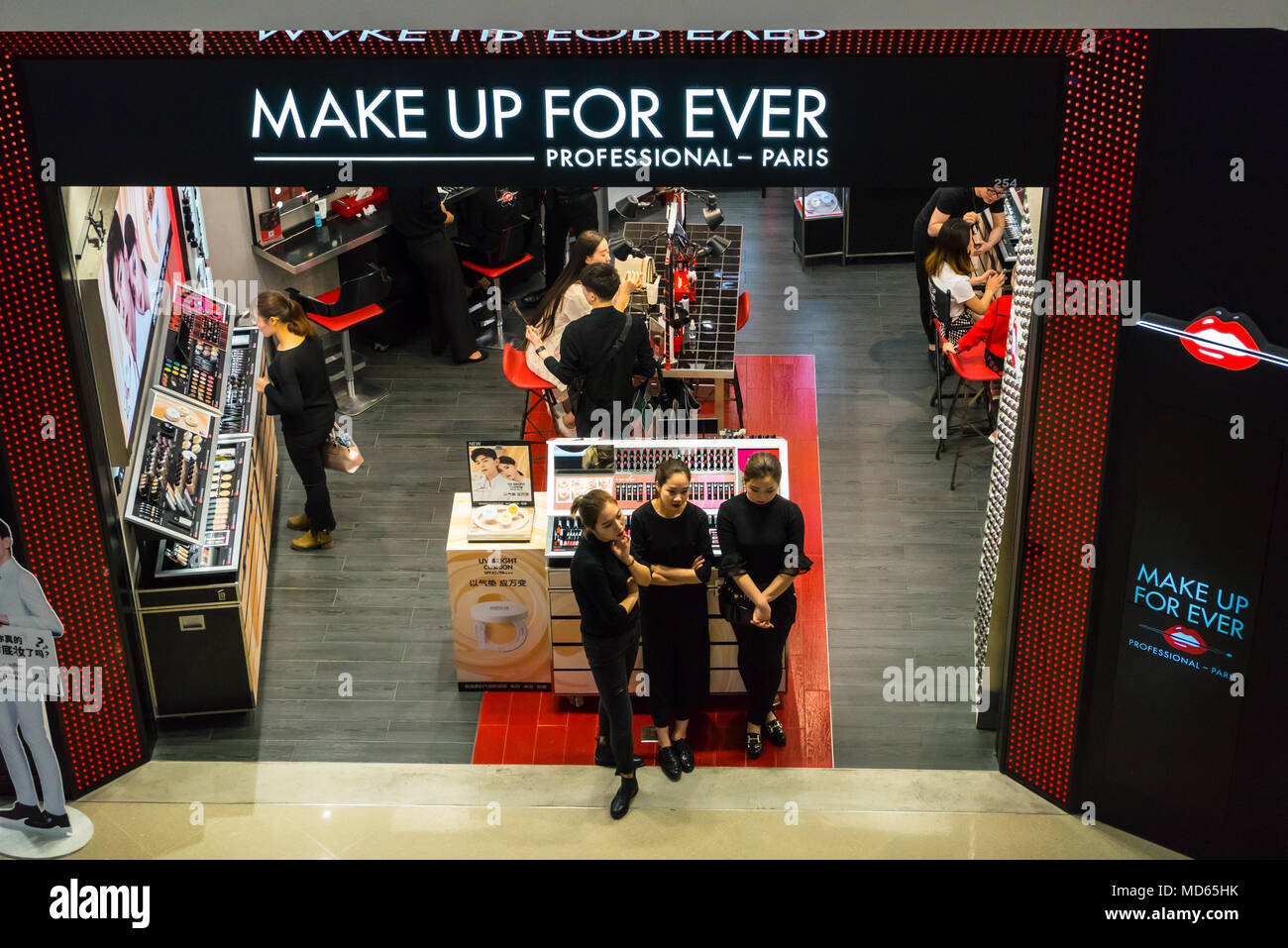 Assistenti Shop Attendere per i clienti di un centro commerciale di Shenzhen, Cina Foto Stock