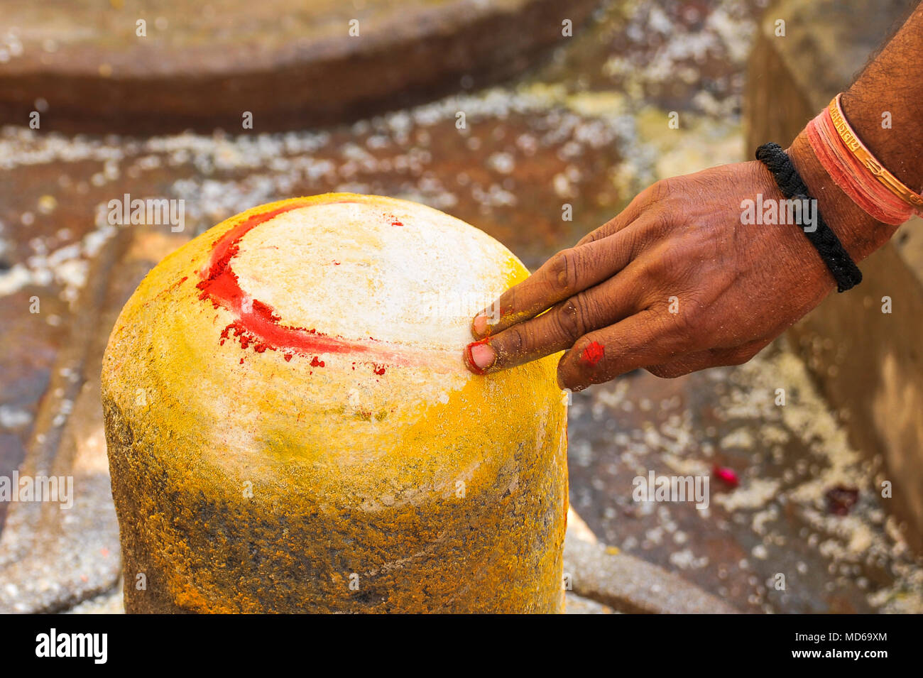 Una mano d'uomo decora un Shiva lingum sul Maha Shivaratri (2/3) Foto Stock