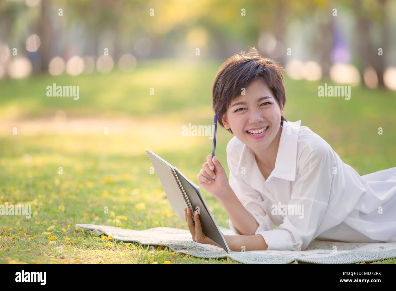 La felicità emozione del tempo rilassante di asiatici più giovane donna con libro e penna in estate park Foto Stock