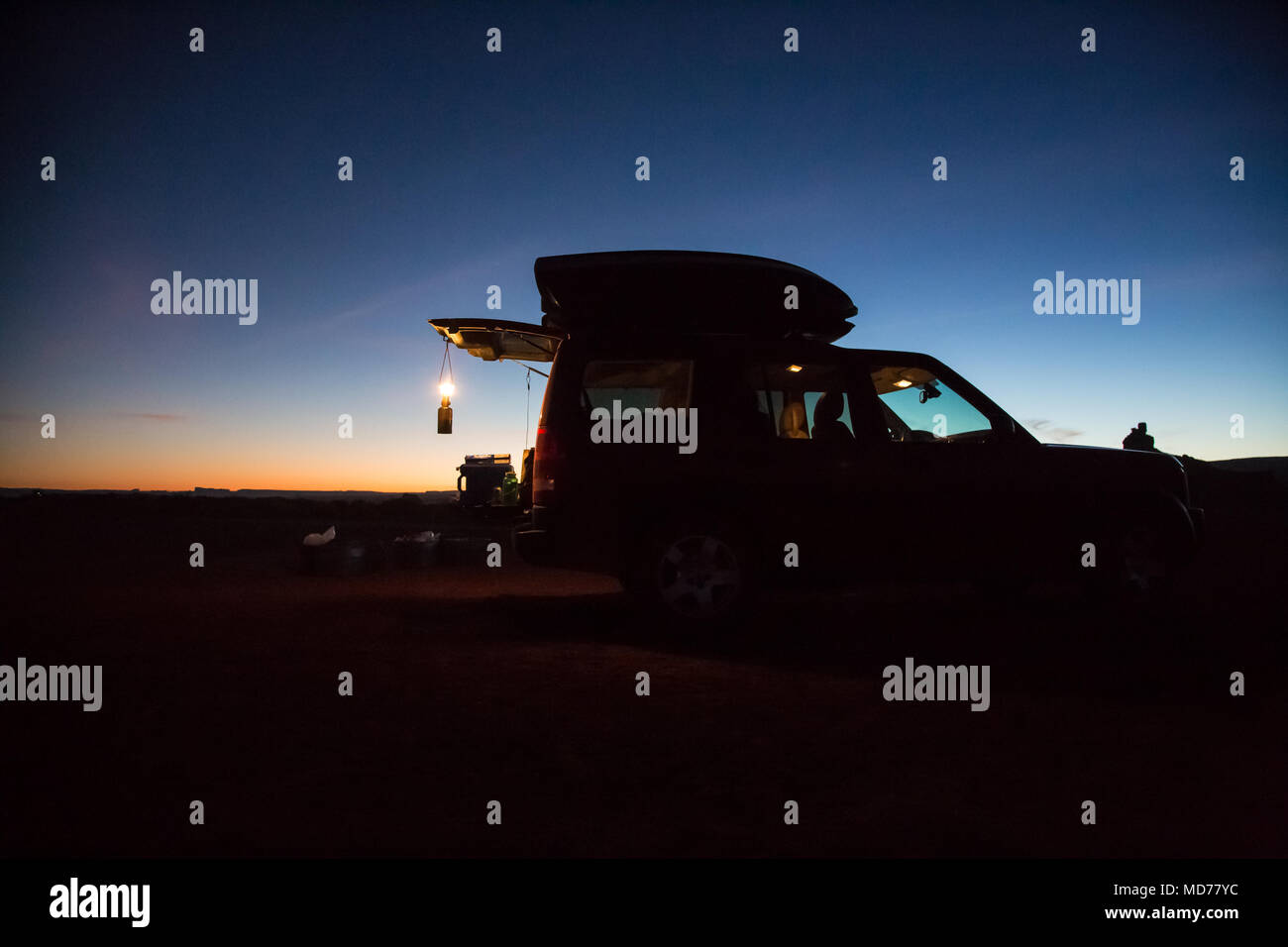 Un incandescente lanterna pende dalla porta sul retro di un SUV rosso nel deserto del sud dell'Utah. Foto Stock