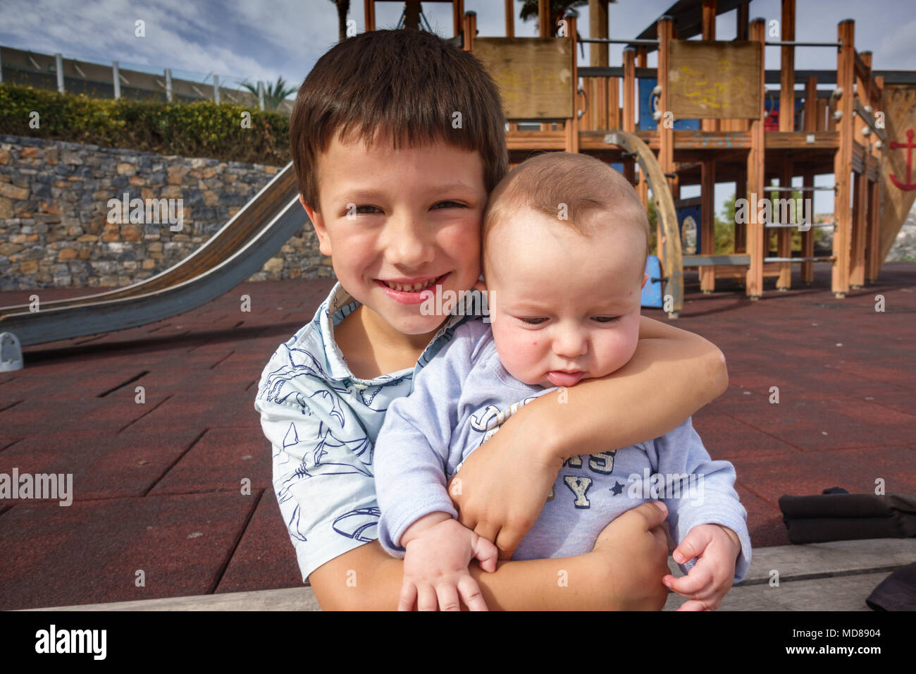 Ragazzo sorridente e baby fratello presso il parco giochi, Grecia Foto Stock