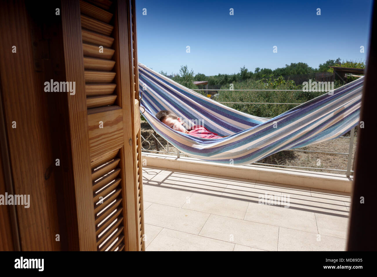 Bambino addormentato in amaca sulla veranda della casa, Creta, Grecia Foto Stock