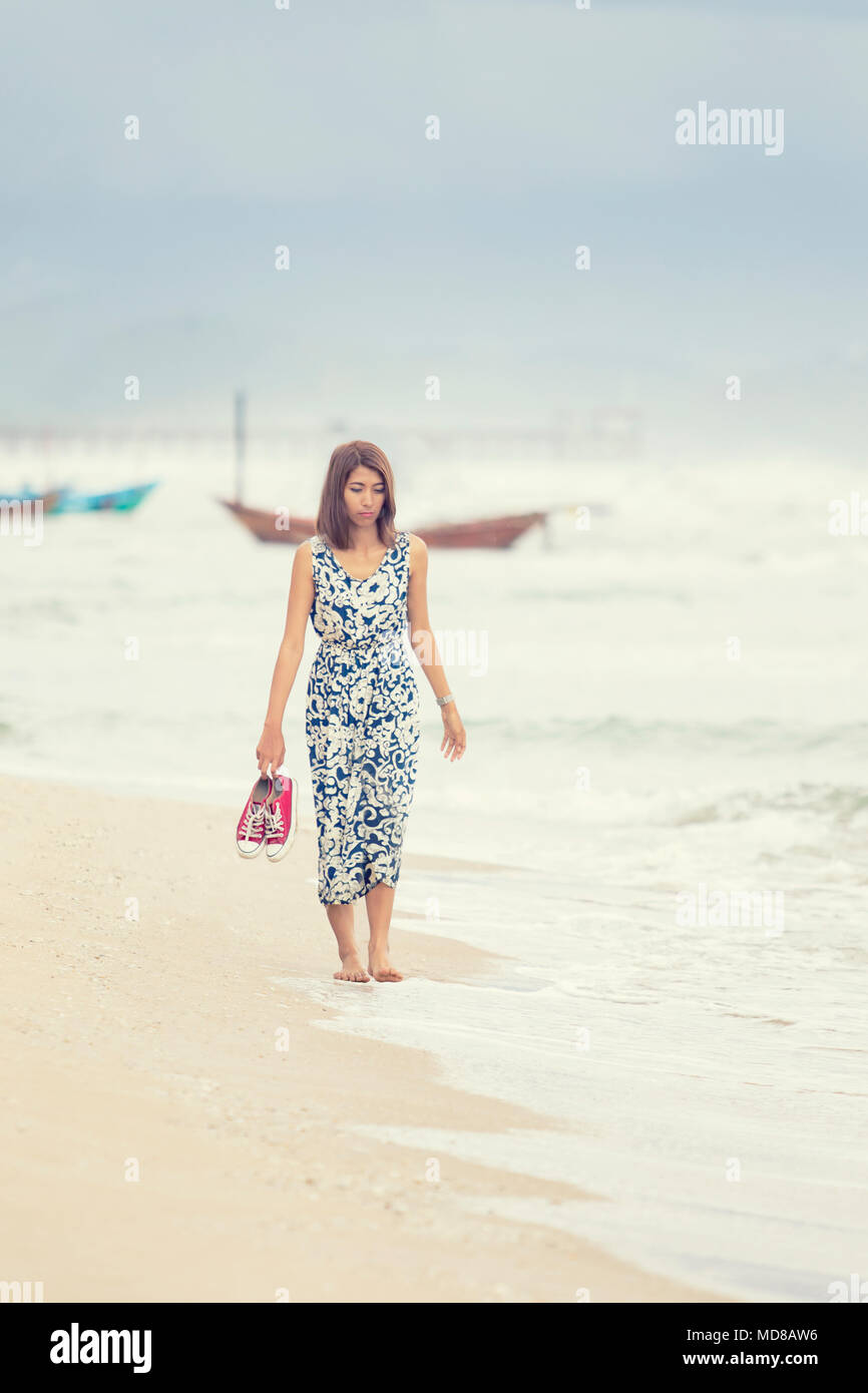 Giovane donna asiatica camminando sulla spiaggia del mare Foto Stock