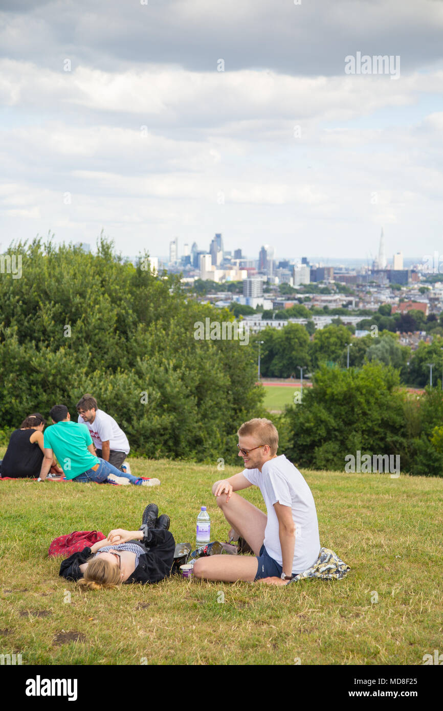 Le persone a rilassarsi e godere della vista panoramica della skyline di Londra un pomeriggio estivo sulla Collina del Parlamento su Hampstead Heath nel nord di Londra Foto Stock