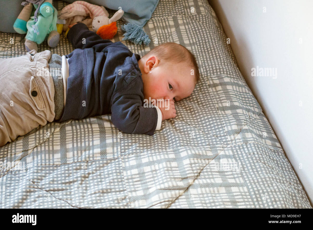 Baby boy in appoggio e la suzione del pollice sul letto, Grecia Foto Stock