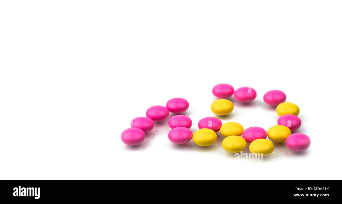Pila di rosa e giallo round compresse rivestite con zucchero pillole isolato su sfondo bianco con copia spazio. Pillole colorate per il trattamento anti-ansia, anti Foto Stock